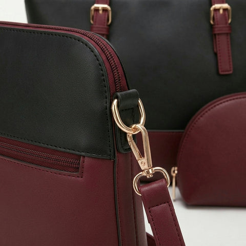 Close up of a maroon handbag with gold clasp and black top section.